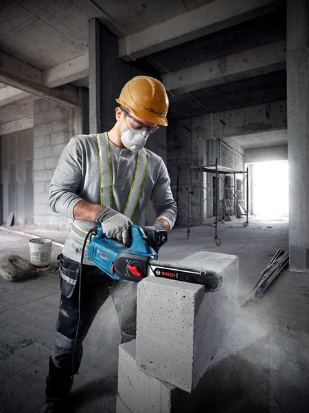 GAC 250 A person wearing safety equipment uses an AAC block cutter on a concrete block.