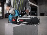 A person wearing safety equipment uses an AAC block cutter on a concrete block.