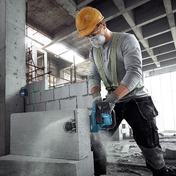 GAC 250 A person wearing safety equipment cuts an AAC block using a power cutter.