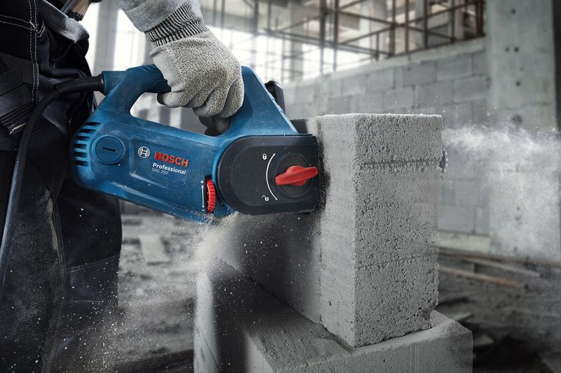 GAC 250 A person wearing safety equipment cuts an AAC block using a blue power cutter.