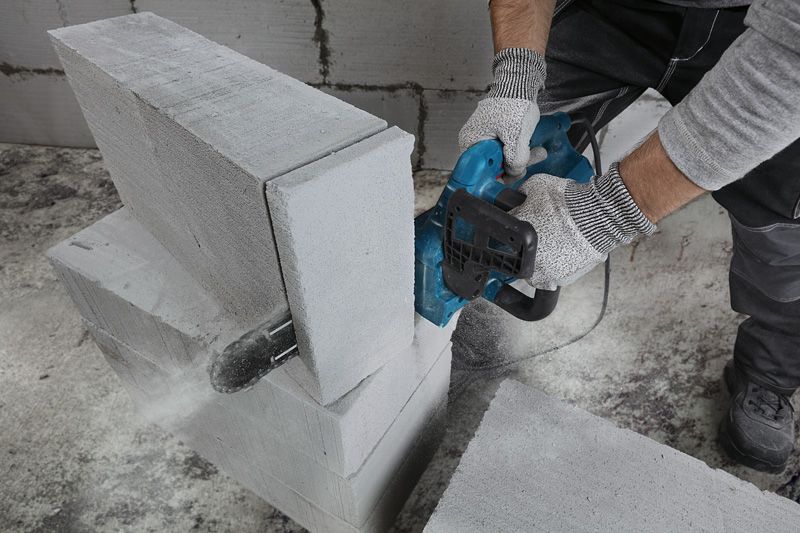 GAC 250 A person wearing safety equipment cuts an AAC block using an electric cutter.