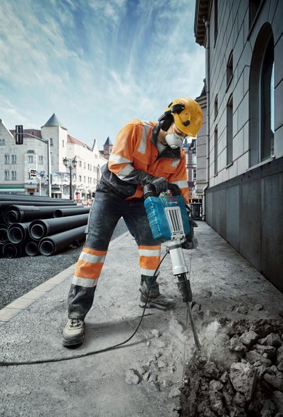 GSH 14 C A person wearing safety equipment breaks pavement with a power breaker on a city street.
