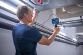 A person inspects inside an air duct using an inspection camera.