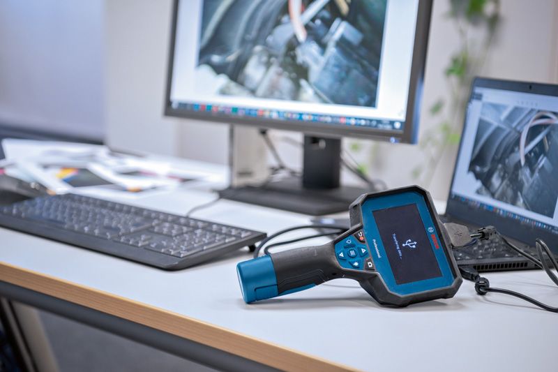 Inspection camera on a desk connected to a computer displaying engine images.