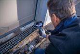 Person wearing safety equipment uses an inspection camera to examine a drain.