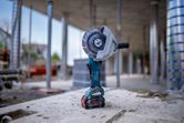 Cordless angle grinder standing upright on a concrete surface at a construction site.