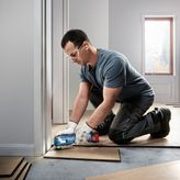 Bosch GOP 185-LI cordless multi-cutter trims floorboards.