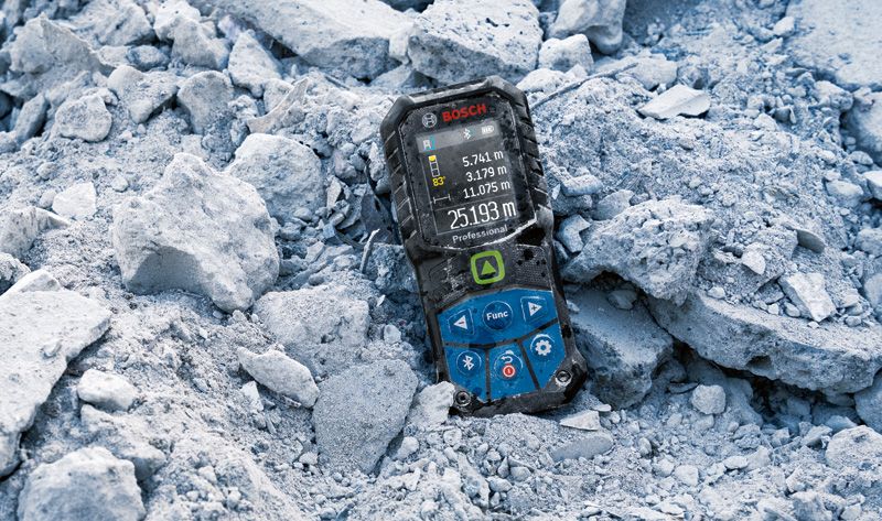Laser measure resting on broken concrete rubble at a worksite.