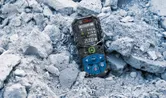 Laser measure displaying distance values lies on rough construction debris.