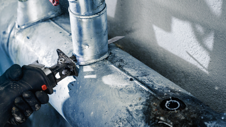 PRO Metal Demolition S1125VF Blade, 1.25 x 19 x 225 mm, 5 pcs Person wearing safety equipment cuts a metal pipe with a power tool.