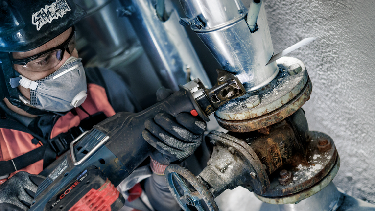 PRO Metal Demolition S1125VF Blade, 1.25 x 19 x 225 mm, 5 pcs A person wearing safety equipment uses a reciprocating saw to cut a corroded pipe.