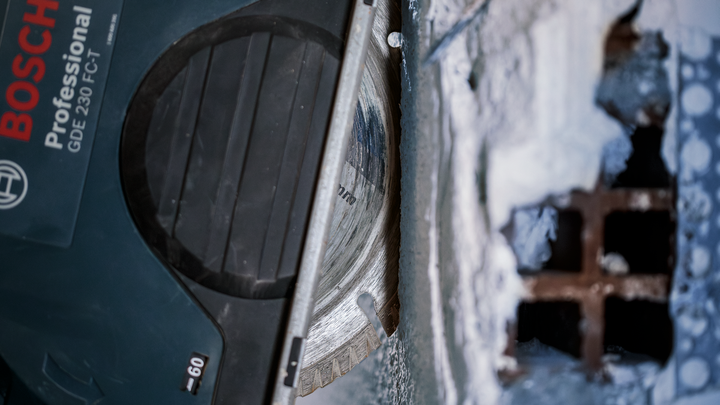 Object #200456642: 3087975_app_web_05 Diamond saw blade cutting through concrete near a metal grate.