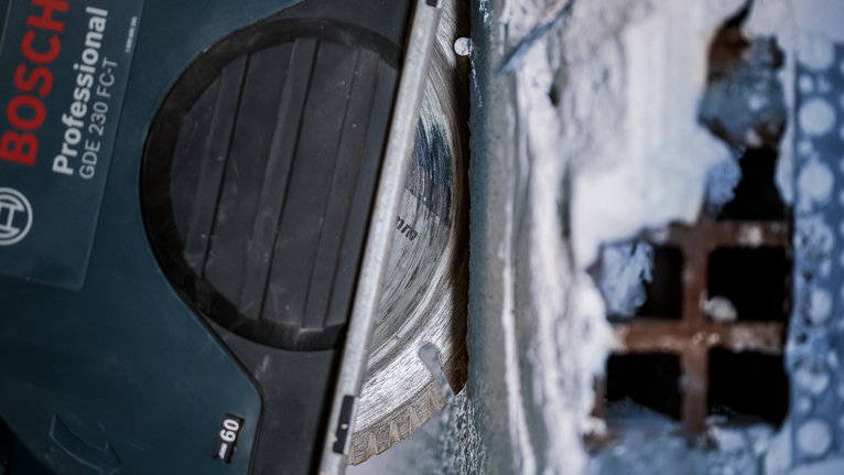 PRO Multi Material Diamond Disc, 180 x 22.23 mm Diamond saw blade cutting through concrete near a metal grate.