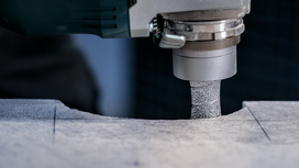 A power tool grinds a precise curved edge into a marked stone surface.
