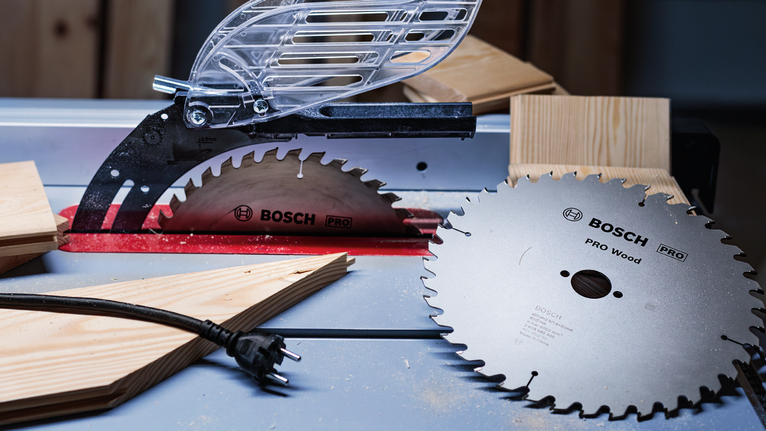 Circular saw blades and wooden planks placed on a workbench in a workshop.
