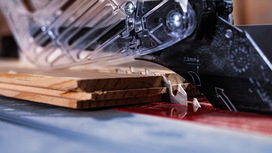 Circular saw blade cutting stacked wooden planks on a workbench.