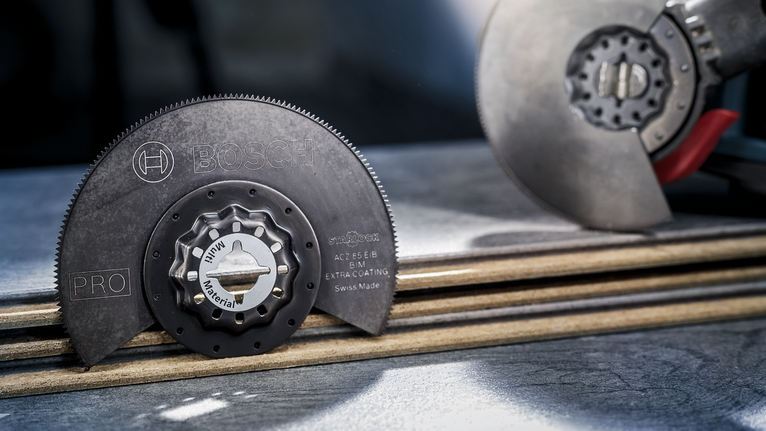 PRO ACZ 85 EIB Multitool Blade, 85 mm Circular saw blade and tool placed on stacked boards in a workshop.