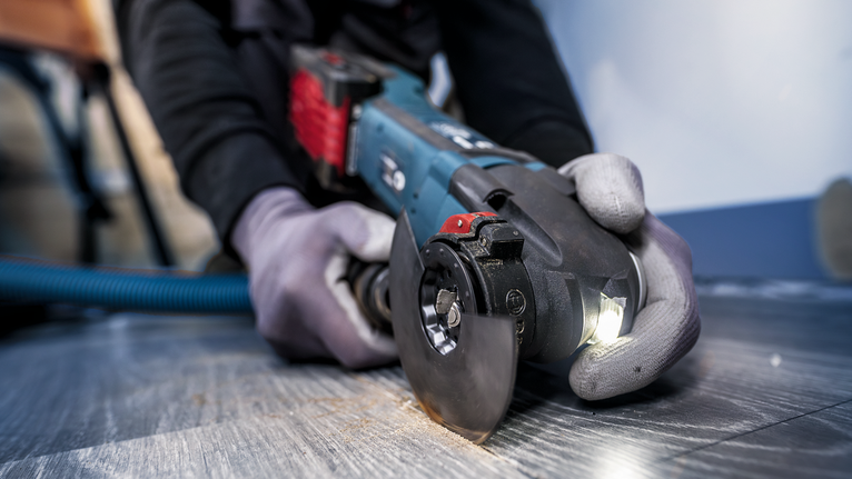 PRO ACZ 85 EIB Multitool Blade, 85 mm Person wearing safety equipment uses an angle grinder to cut a tile floor.