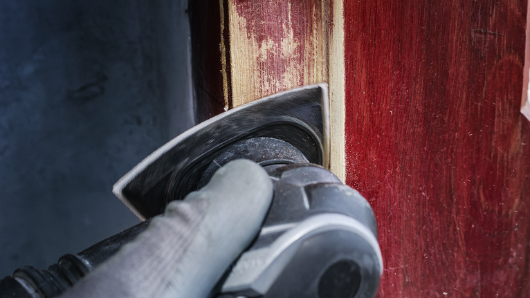 PRO AVZ 93 G Multitool Accessory, 93 mm Person wearing safety equipment sands paint off a wooden door with a power tool.