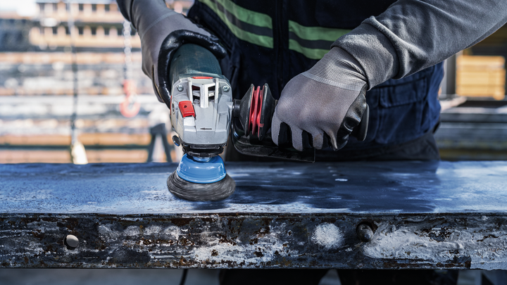 Object #200456906: 3089943_app_web_03 Person wearing safety equipment polishes a metal surface with a power tool.