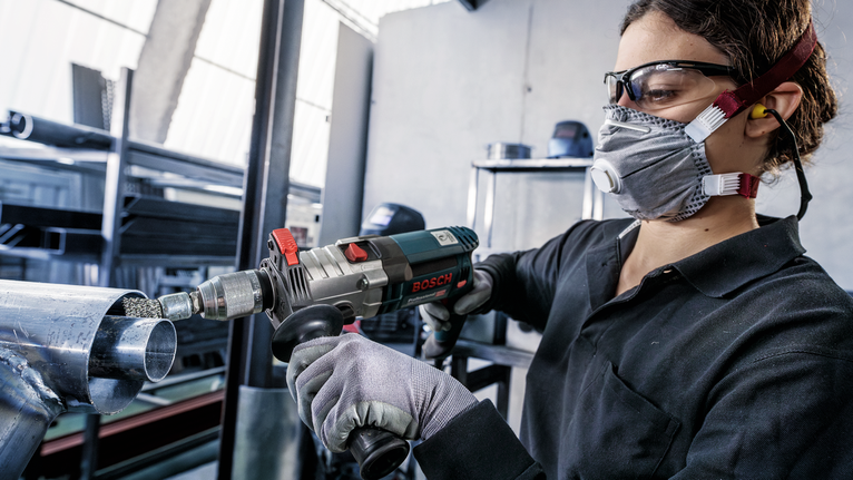PRO Metal clean End Brush, Straight Shank, 25 x 0.3 mm Person wearing safety equipment grinds the end of a metal pipe with a power tool.