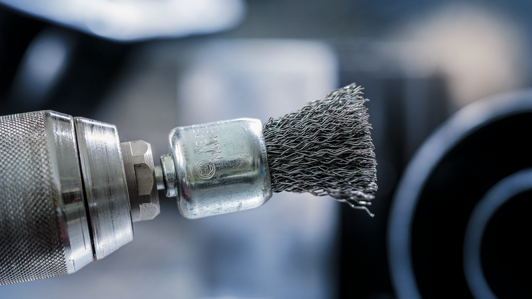 PRO Metal clean End Brush, Straight Shank, 25 x 0.3 mm Close-up of a power drill fitted with a wire brush attachment.
