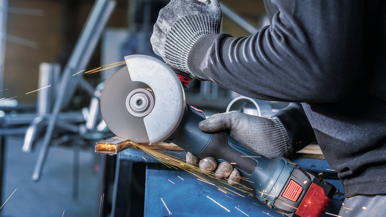 PRO Stainless Steel and Metal Bonded Cutting Disc, 125 x 1 x 22.23 mm, X-Lock, Straight Person wearing safety equipment grinds metal, producing sparks.