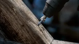 Rotary tool grinding a groove into a wooden beam.