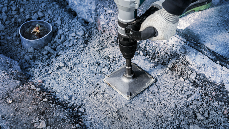 PRO SDS max Tamping Plate, 150 x 150 mm Person wearing safety equipment operates a drill on a concrete surface.