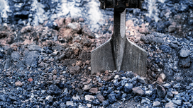Chisel bit breaking up compacted gravel on a construction site.