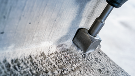 Rotary hammer chisel breaking up concrete at the base of a wall.
