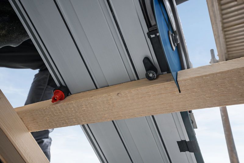 Track saw cutting through a wooden beam on a construction site.