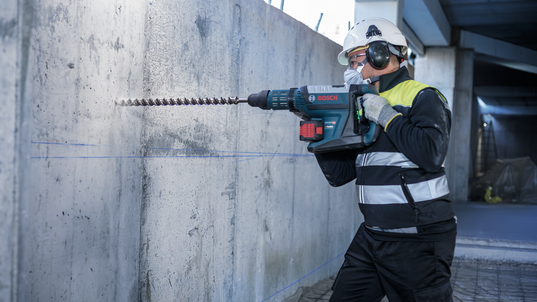 PRO SDS-max-7 Drill Bit, 35x400x520 mm Person wearing safety equipment uses a rotary hammer to drill into a concrete wall.