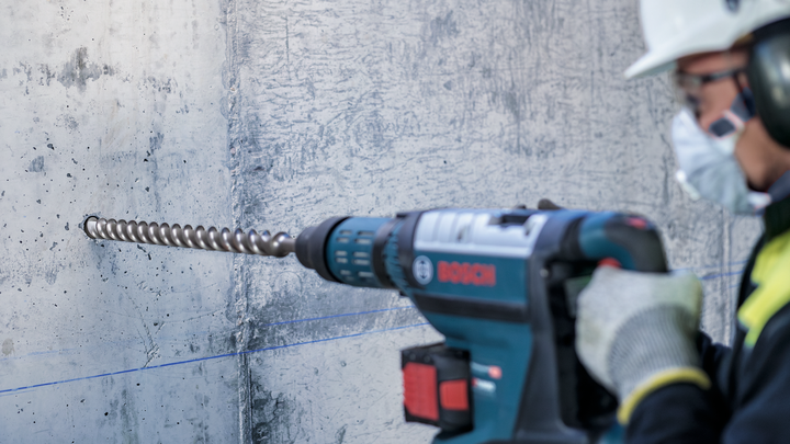 Object #200461134: 3065448_app_web_5 Person wearing safety equipment drills into concrete with a rotary hammer.