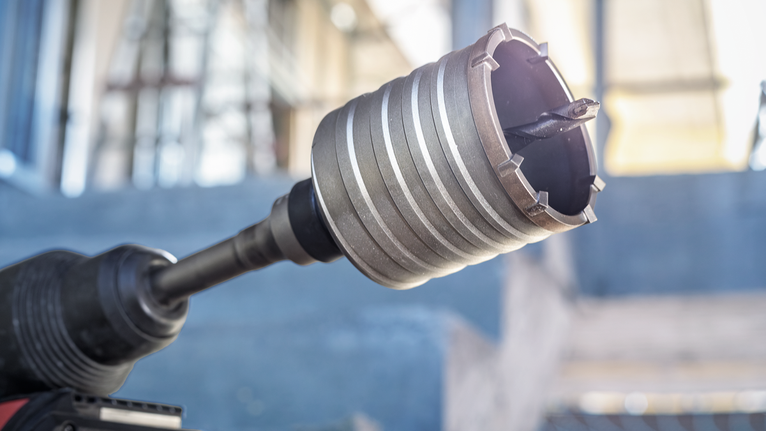 Close-up of a rotary hammer drill with a core bit attached at a construction site.