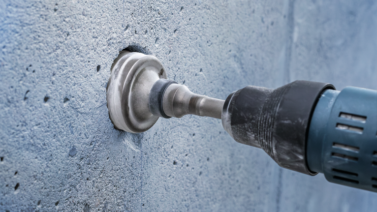 Hole saw drilling into a concrete wall.