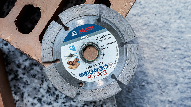 Segmented diamond blade for cutting brick and concrete rests on a building block.