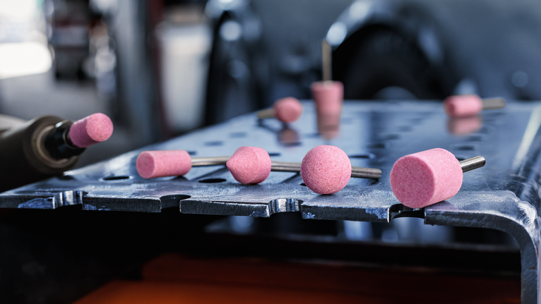 PRO Steel Mounted Point Set, 25 x 24; 15 x 30; 15 x 30; 25 x 25; 20 x 25 mm, G60; G60; G60; G60; G60, 5 pcs Grinding stones scattered on a metal workbench in an industrial setting.