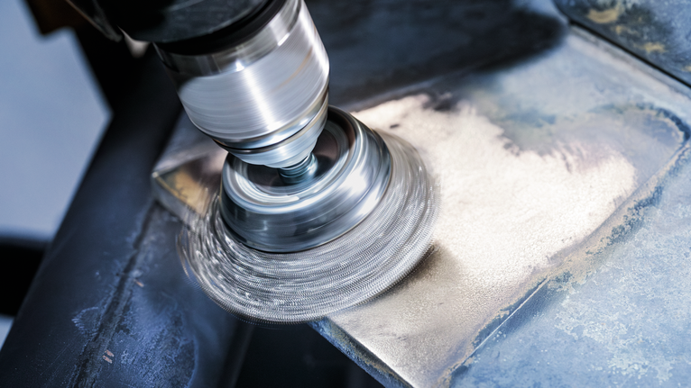 PRO Metal clean Cup Brush, Straight Shank, 70 x 0.3 mm Angle grinder with wire brush attachment cleaning the surface of a metal sheet.