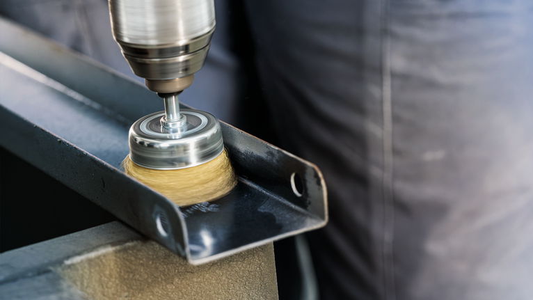 PRO Metal clean Cup Brush, Straight Shank, 70 x 0.3 mm A person uses a drill with a wire brush attachment to clean a metal beam.