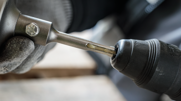 PRO SDS Shank Grease, for Drill and Chisel Person wearing safety equipment inserts a drill bit into a power tool.
