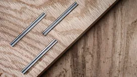 Three grooved metal inlays embedded in a light wooden board.