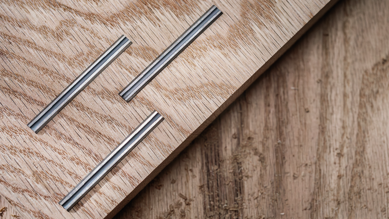 Three grooved metal inlays embedded in a light wooden board.