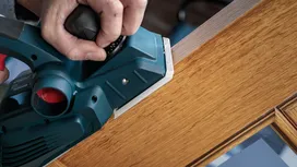 Power planer smoothing the edge of a wooden door.