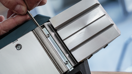 Person adjusting a metal planer blade with a tool.