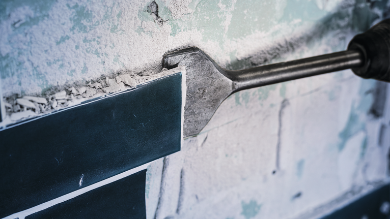 PRO SDS max-4C Tile Chisel, 80 x 300 mm Chisel tool removing ceramic tile from a dusty wall surface.