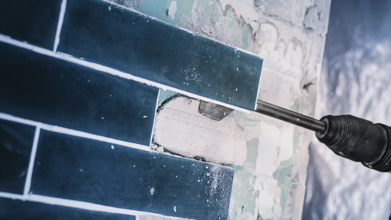 PRO SDS max-4C Tile Chisel, 80 x 300 mm Power tool chipping blue tiles from a wall.