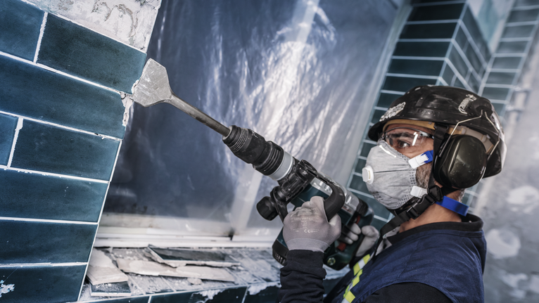 PRO SDS max-4C Tile Chisel, 80 x 300 mm Person wearing safety equipment uses a power tool to remove ceramic tiles from a wall.