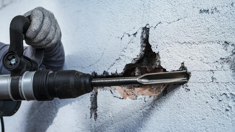 PRO SDS max Hollow Gouging Chisel, 26 x 300 mm A person wearing safety equipment uses a rotary hammer to chisel into a wall.