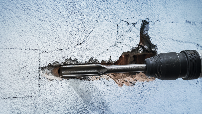 PRO SDS max Hollow Gouging Chisel, 26 x 300 mm Rotary hammer chisel breaking a channel in a painted concrete wall.